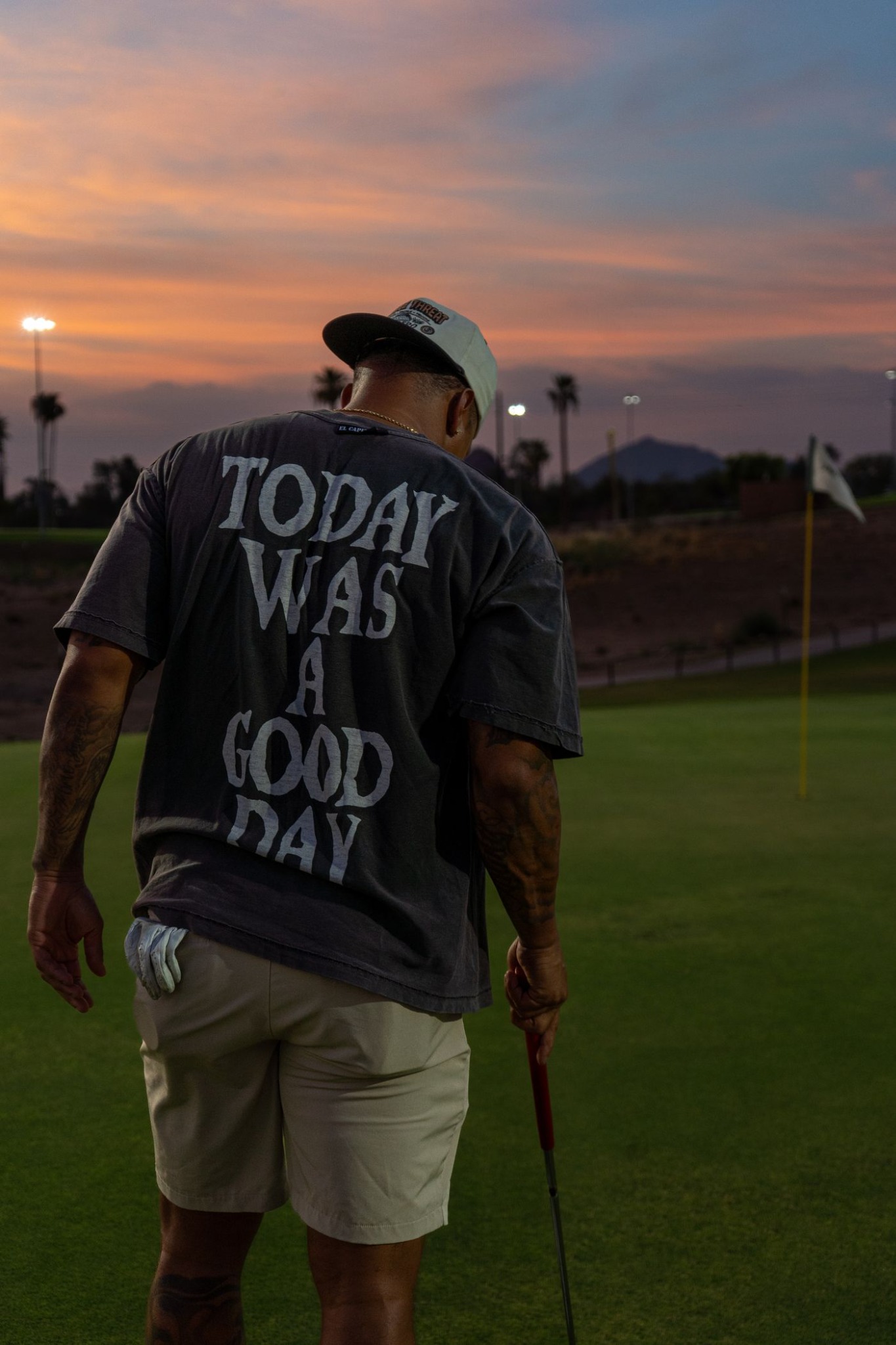 Golfer walking toward the flag at sunset in a “Today was a good day” shirt