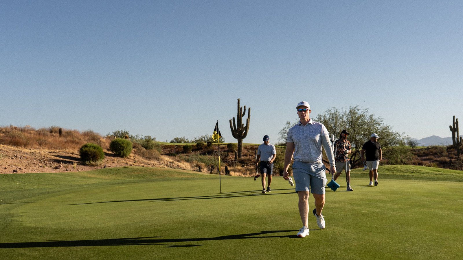 Group walking off a desert green past a saguaro