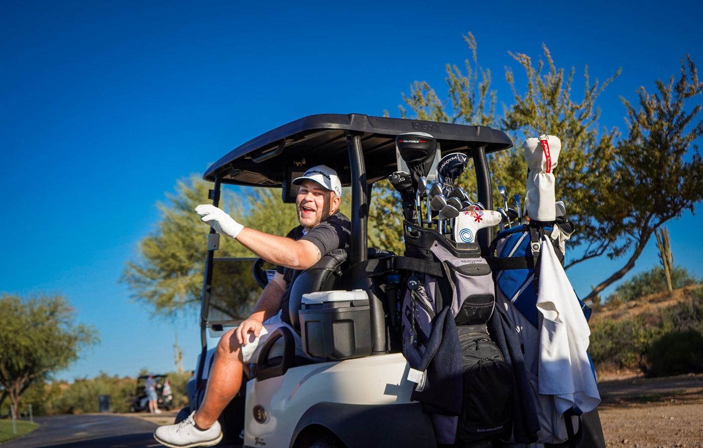 Golfer laughing and waving from his cart